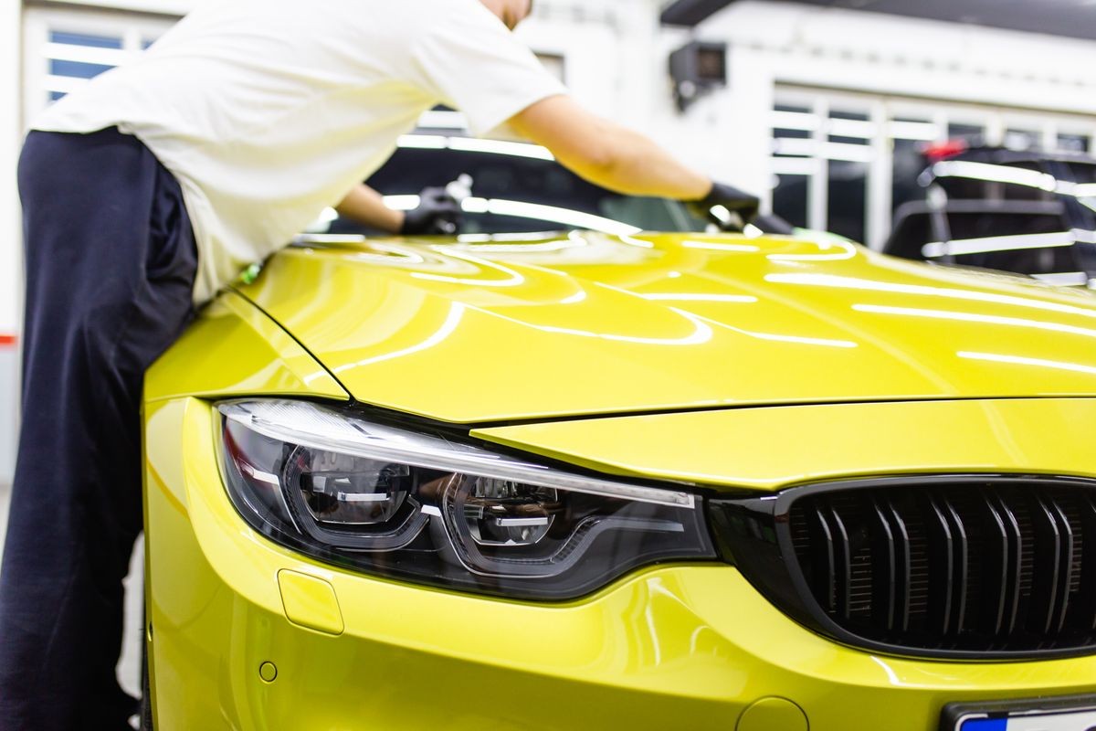 A man cleaning car with microfiber cloth, car detailing (or valeting) concept. Selective focus. 